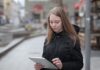 Młoda kobieta korzysta z tabletu na miejskiej ulicy z publicznym Wi‑Fi