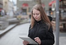 Młoda kobieta korzysta z tabletu na miejskiej ulicy z publicznym Wi‑Fi
