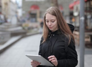 Bezpieczne korzystanie z publicznego Wi‑Fi: praktyczne wskazówki dla początkujących Młoda kobieta korzysta z tabletu na miejskiej ulicy z publicznym Wi‑Fi