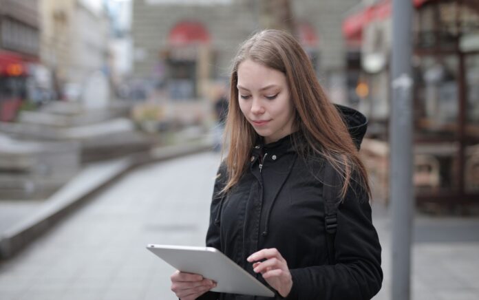 Młoda kobieta korzysta z tabletu na miejskiej ulicy z publicznym Wi‑Fi