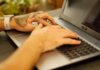 Wytatuowane dłonie piszące na klawiaturze laptopa z Linuxem