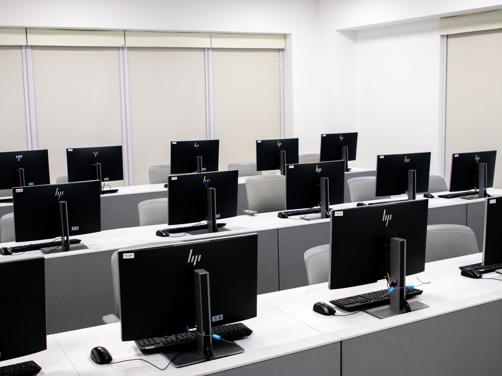 Nowoczesna, minimalistyczna sala komputerowa z rzędami czarnych monitorów
